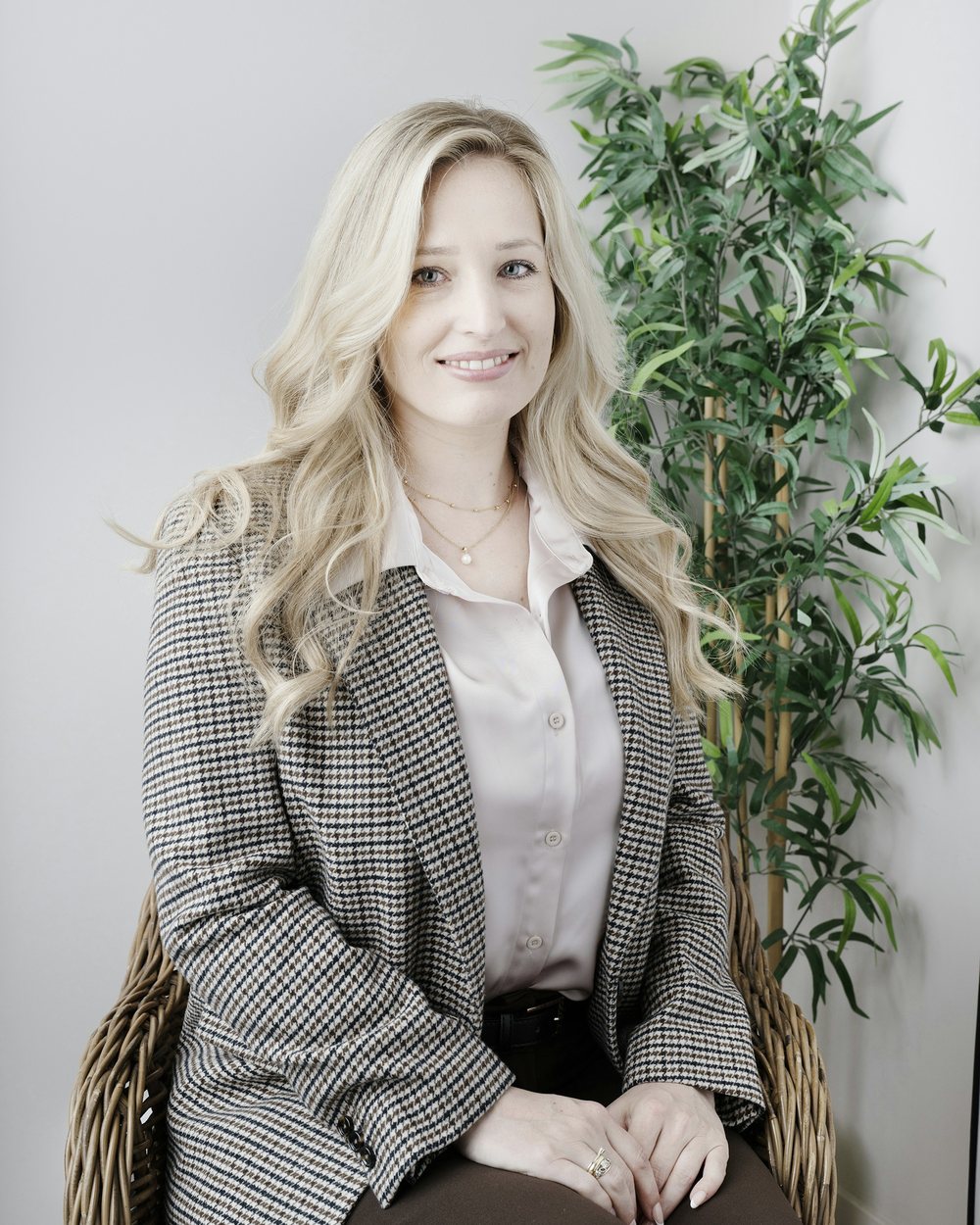 Imogen Haynes, seated in a tailored check blazer and silk blouse